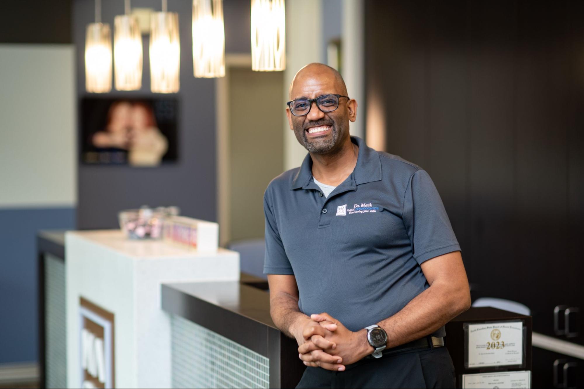 Smiling orthodontist in a welcoming office setting, promoting stress-free treatment and patient support at Mack Orthodontics.