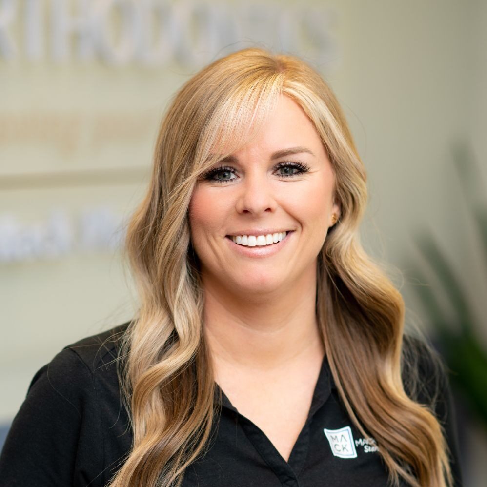 Smiling woman in a Mack Orthodontics shirt, representing the friendly team dedicated to providing braces and Invisalign services in Burlington and Hillsborough, NC.